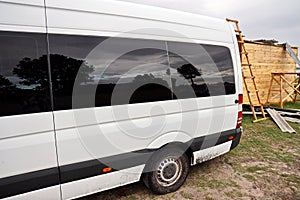 Close-up view of a minibus and cars standing on the shore of a lake. The reflection in the windows of the car.