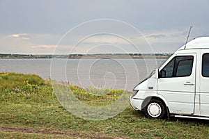 Close-up view of a minibus and cars standing on the shore of a lake. The reflection in the windows of the car.