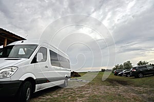 Close-up view of a minibus and cars standing on the shore of a lake. The reflection in the windows of the car.