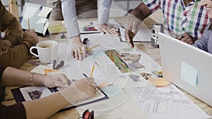 Close-up view of mixed race group of people working at the table. Team discussing architectural design, start-up company