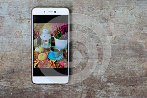 Close up view of a mobile phone with an autumn background screen photo on old rustic wooden background