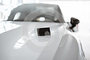 Close-up view of modern keys lying on the hood of a new car.