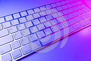 Close up view of a modern laptop computer keyboard keys. Soft lightning. Computer keyboard close up in pink and blue tones