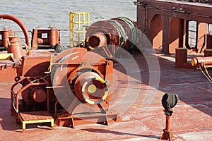 Close up view on mooring winches in aft stern maneuvering station with bollards, bitts and ropes of cargo container vessel.