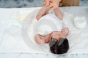Close up view mother change diaper or napkin for newborn baby lie on white bed after she excrete pee or stool