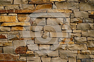 Close-up view of a natural stone wall with irregular beige and brown blocks forming a rustic pattern.