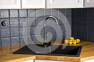 Close up view of new modern kitchen solid wood butcher block oak counter with built in black rectangular granite sink.