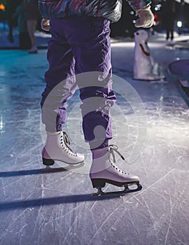 Close up view of new white ice skates boots on rink in motion, girl ice skating on arena, concept of ice skating in winter,