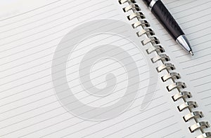 Close up view of note book with silver metal binder and pen with