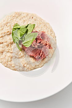 Close-up view oatmeal porridge with lowfat ham and fresh spinach. photo