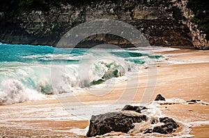 Close-up view of ocean waves breaking on the beach. Turquoise sea and white tropical beach. Kelingking beach on Nusa Penida, Bali