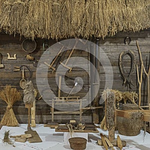 Close-up view with old attributes of rural life. Yarn, sickle, seive, clamp, log, saw, spinning wheel and other things