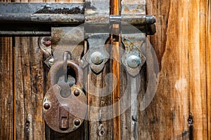 Close up view of the old rusty padlock on a aged gray wooden door