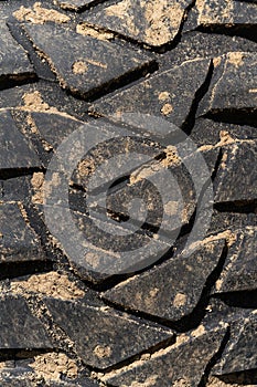 Close-up view of old used rubber mud terrain tire with worn wear-resistant tread
