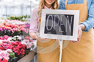 Close-up view of Open board in hands of owners of greenhouse standing among