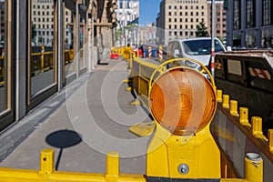 Orange amber caution light and plastic barriers to warn for construction site.