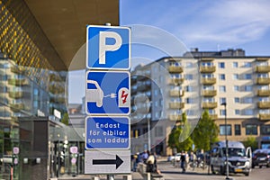 Close up view of parking sign for charging electric vehicles in parking lot near mall.