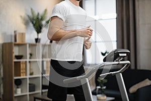 Close up view of part of body of young sportsman running on treadmill