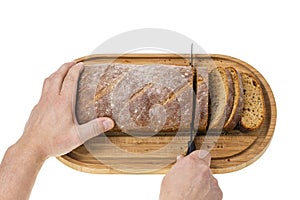 Close up view of partially sliced loaf of rye bread on wooden cutting board with bread knife.