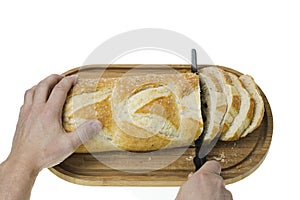 Close up view of partially sliced loaf of white bread on wooden cutting board with bread knife.