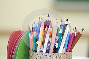 A close-up view of a pen holder filled with colorful pencils, resting on a wooden table. photo