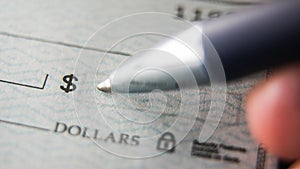 Close up view of a pen ready to sign a blank check on a desk for a financial transaction