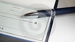 Close-Up view of a pen resting on a blank check on a desk
