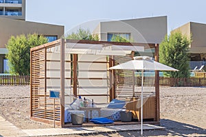 Close up view of personal wooden covered cabana on the sandy beach of the hotel with a sun lounger, a sunshade,