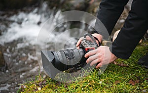 Close up view of a photo video mirrorless camera held in hand by a male photographer in nature landscape