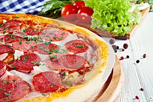 Close up view on pizza on white wooden background with ingridients.