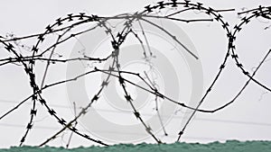 Close up view of prison barbed wire. Barbed wire in jail. Fence with barbed wire against grey sky.