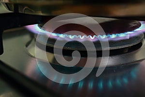 Close-up view on propane butane fuel LPG or petroleum gas kitchen stove hob with blue flame and metal cooking pot