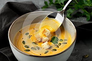 Close-up view of pumpkin soup in deep bowl with seeds and crackers