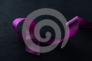 Close up view of purple ribbon on black background.