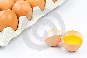 Close-up view of raw chicken eggs in egg box on white wooden background.