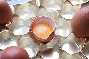 Close-up view of raw chicken eggs in egg box on white wooden background