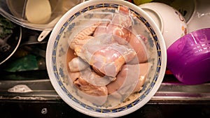 Close up view of raw chicken pieces being defrost in a bowl of lukewarm water