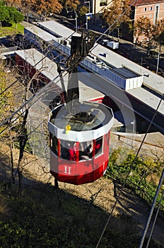 Close-up view of red cablecar with people over the port in Barcelona. Transportation from Montjuic to the harbor of Barcelona.