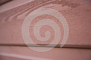 Close up view of a red grainy wood house plank