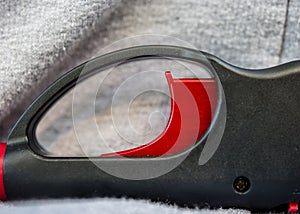 Close up view of red igniter button on black automatic lighter.  Abstract curves and design