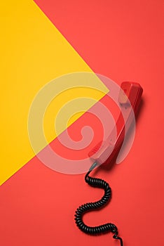 Close-up view of red telephone receiver with curly cord