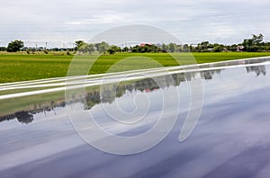 A close-up view of a reflection on a blue solar panel over green rice paddies