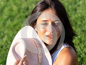 Close-up view of a relaxed woman looking away while sitting on the grass in a sunny day