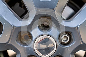 Close up view of the rim and wheel of a car with two broken lug nuts