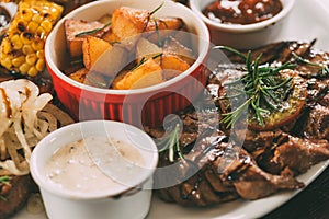 close-up view of roasted potatoes, grilled vegetables and meat with sauces