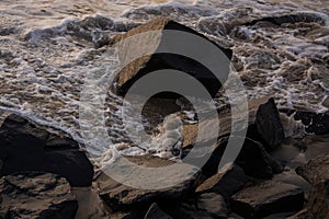close-up view of rocks with water waves tides splashing.