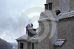 Close up view of roof covered by red tile in the snow with several chimneys. Ancient Bran Castle, also called Dracula`s Castle.