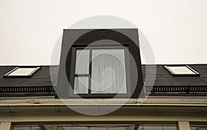 Close up view of roof window on black roof of modern townhouse