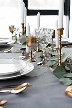 close up view of rustic table arrangement with eucalyptus, vintage cutlery, candles in candle holders and empty plates