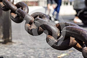 Close up view of rusty metal chain links on a blurred square at background